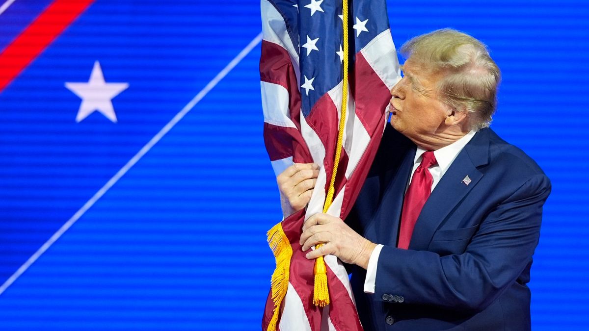 Donald Trump hugs and kisses the American flag as he speaks at the Conservative Political Action Conference in February 2024.