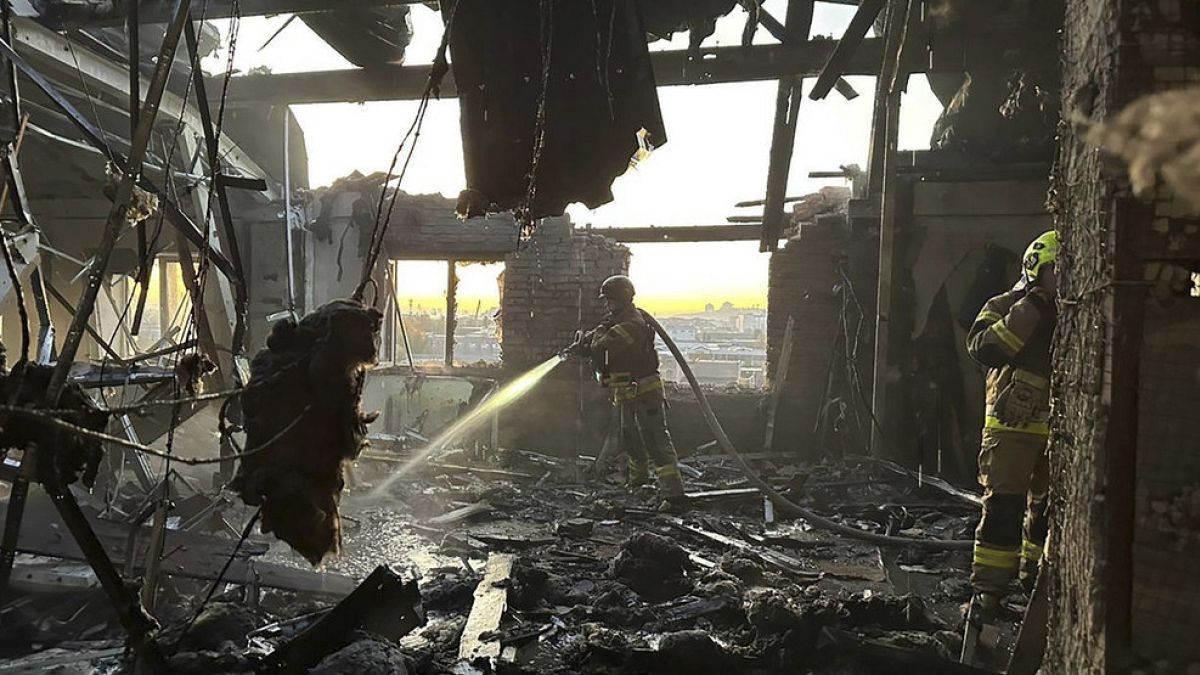 A firefighter hoses the remnants of a building destroyed in Russian strikes.