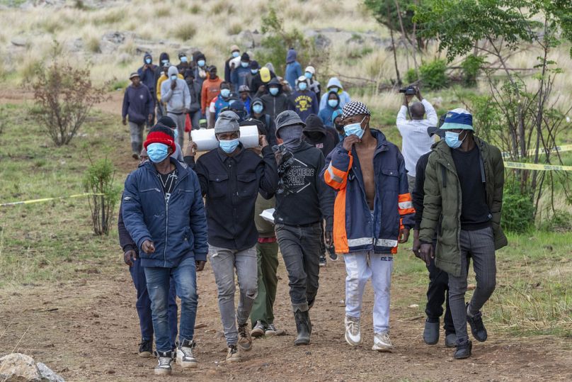 Des secouristes bénévoles et des membres de la communauté quittent un puits de mine où des mineurs illégaux sont piégés dans une mine désaffectée à Stilfontein, en Afrique du Sud, le jeudi 14 novembre 2024. 