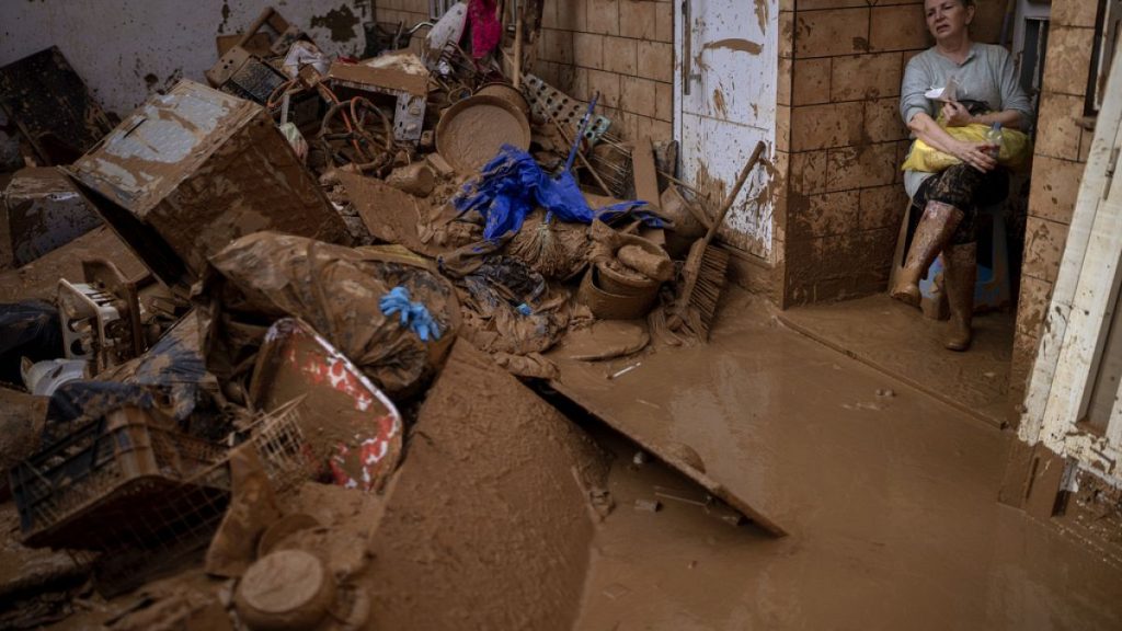 Woman looks down at belongings ruined after devastating flash floods hit parts of Spain