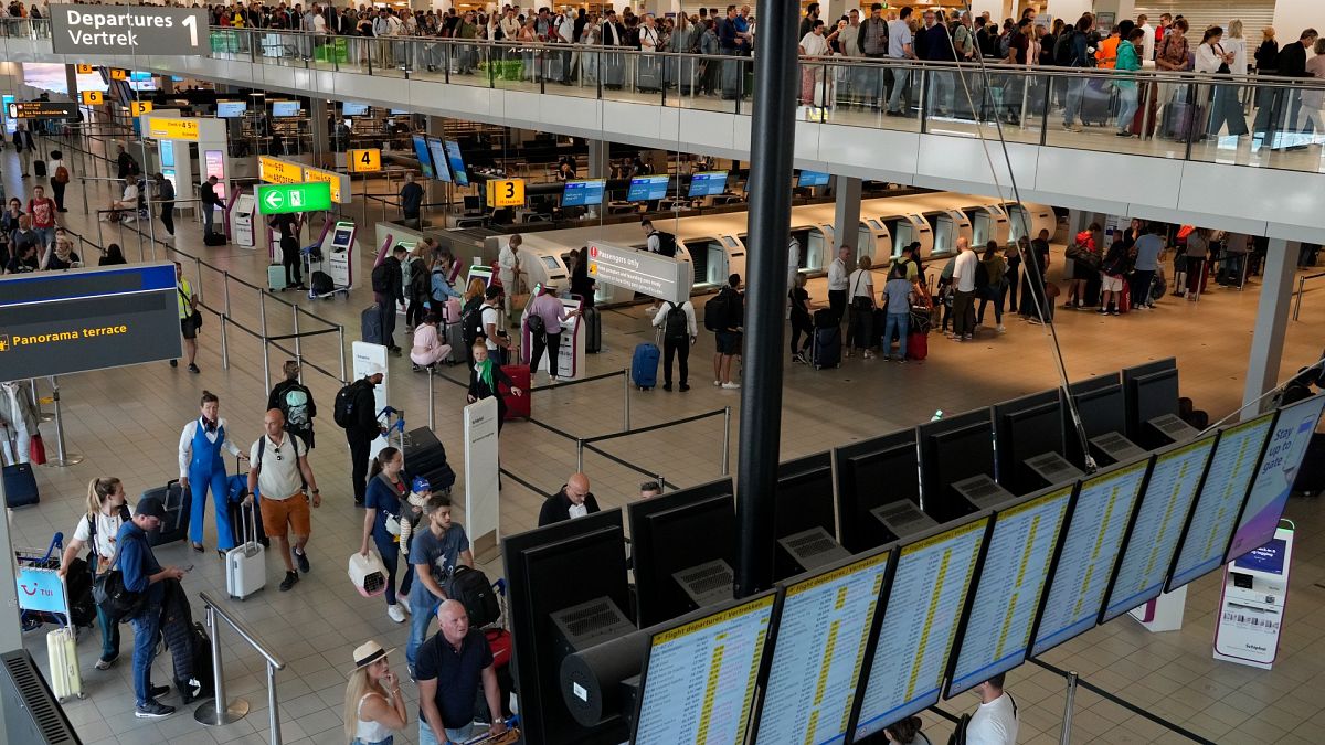 Travelers wait in long lines to check in and board flights at Amsterdam