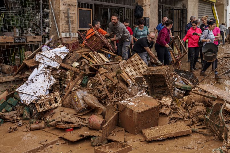 Des gens nettoient la boue d'un magasin touché par les inondations à Chiva, en Espagne, le vendredi 1er novembre 2024.