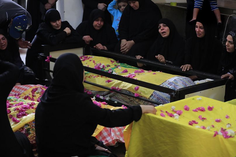 Des femmes pleurent les corps des victimes enveloppées dans des drapeaux du Hezbollah, qui ont été tuées lors d'une frappe aérienne israélienne, lors de funérailles de masse dans le sud du Liban, le 13 novembre 2024.