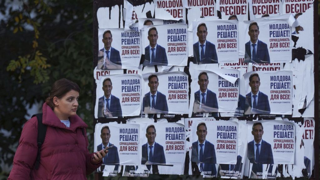 A woman walks past posters displaying Alexandr Stoianoglo, presidential candidate of the Socialists