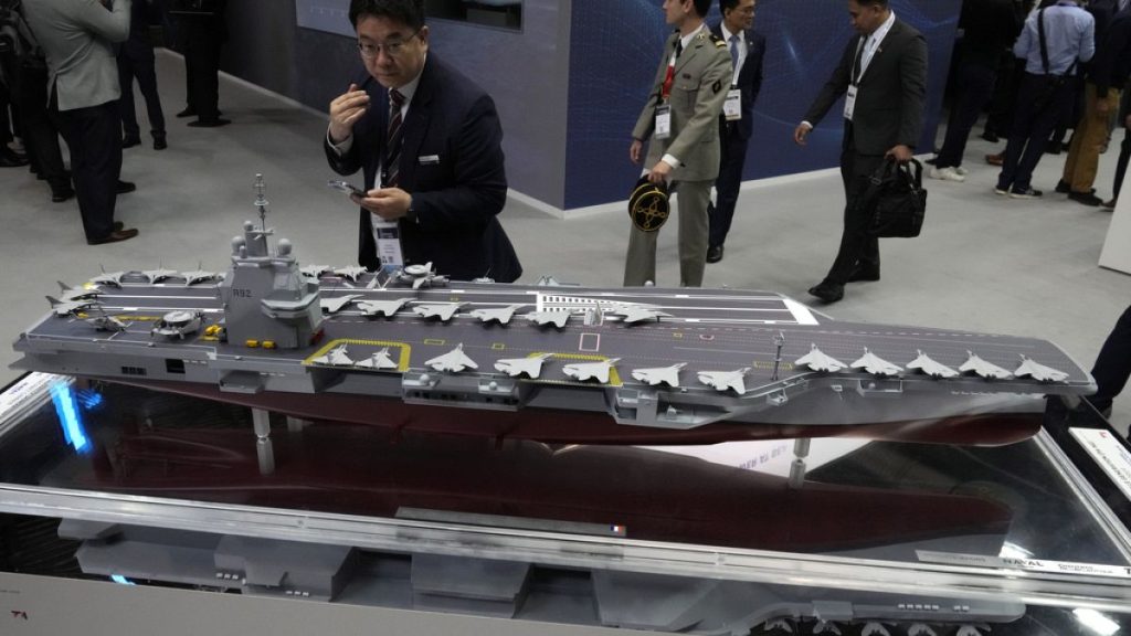 A visitor watches a replica of the the French new generation aircraft carrier during the Euronaval weapons show, Monday, Nov. 4, 2024 in Paris.