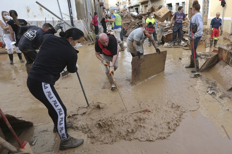 Des habitants et des bénévoles balayent la boue après les inondations à Paiporta, près de Valence, en Espagne, le dimanche 3 novembre 2024.