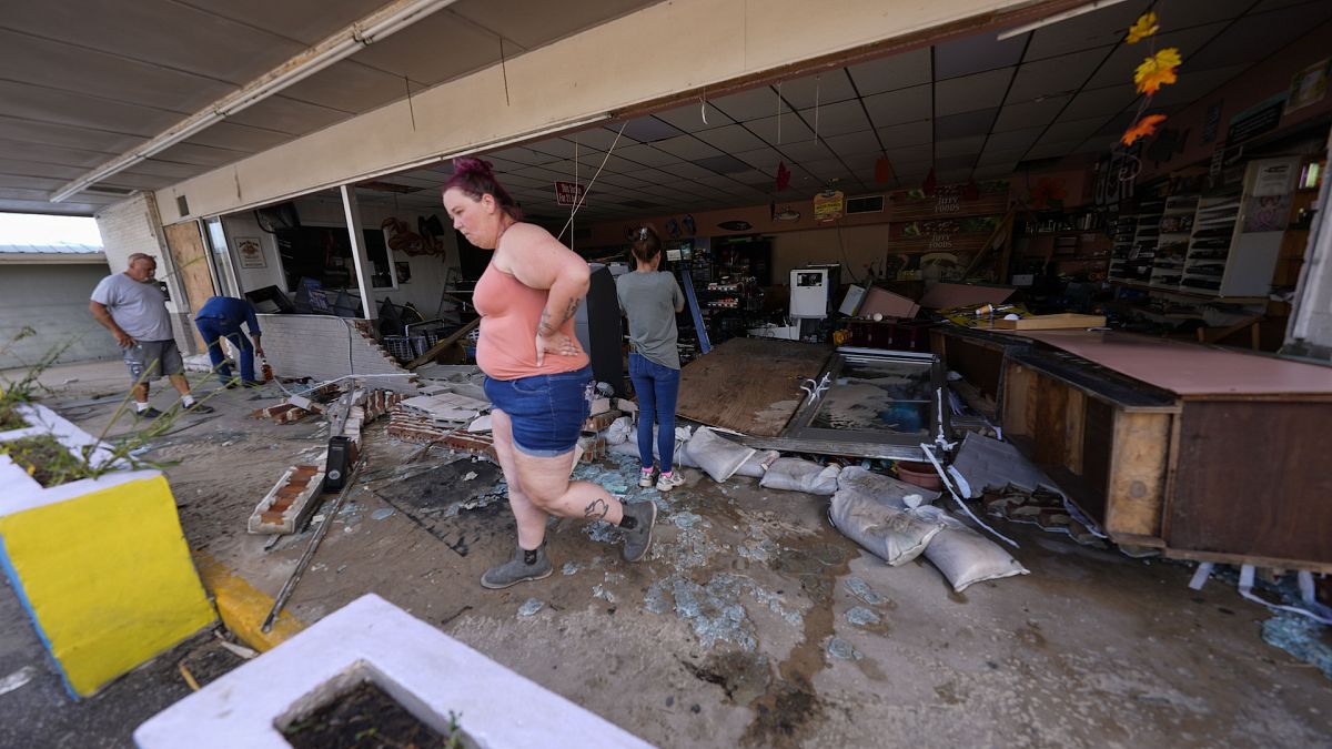 Library picture of an assistant shop manager walking through debris of the damaged shop in the aftermath of Hurricane Helene