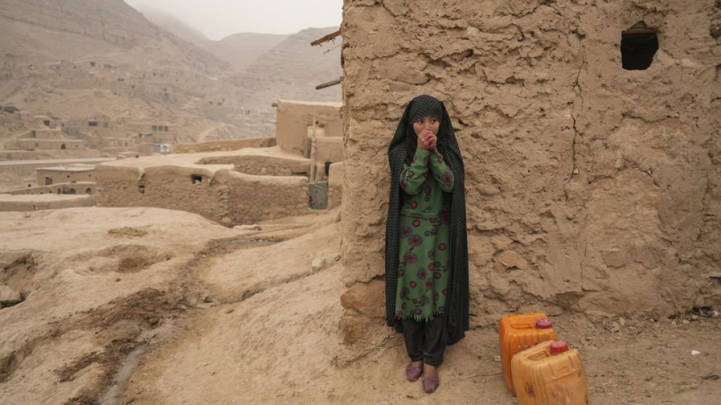 FILE - An Afghan girl warms up her hands as she is resting from carrying the water in Balucha, Afghanistan, Monday, Dec. 14, 2021. (AP Photo/Mstyslav Chernov, File)