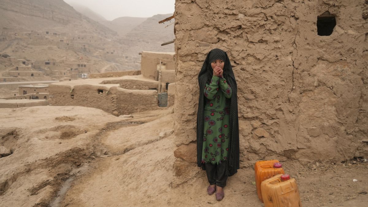 FILE - An Afghan girl warms up her hands as she is resting from carrying the water in Balucha, Afghanistan, Monday, Dec. 14, 2021. (AP Photo/Mstyslav Chernov, File)