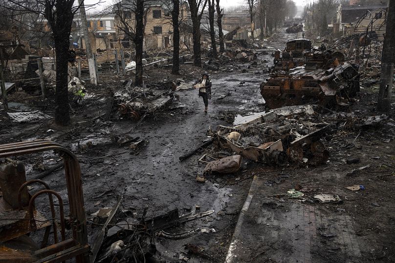 Une femme marche au milieu des chars russes détruits à Bucha, dans la banlieue de Kiev, le 3 avril 2022.