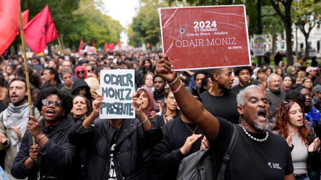 People carry signs with the name of Odair Moniz, a Black man of Cape Verdean origin who was fatally shot by police Monday, during a protest against racism and police violence.