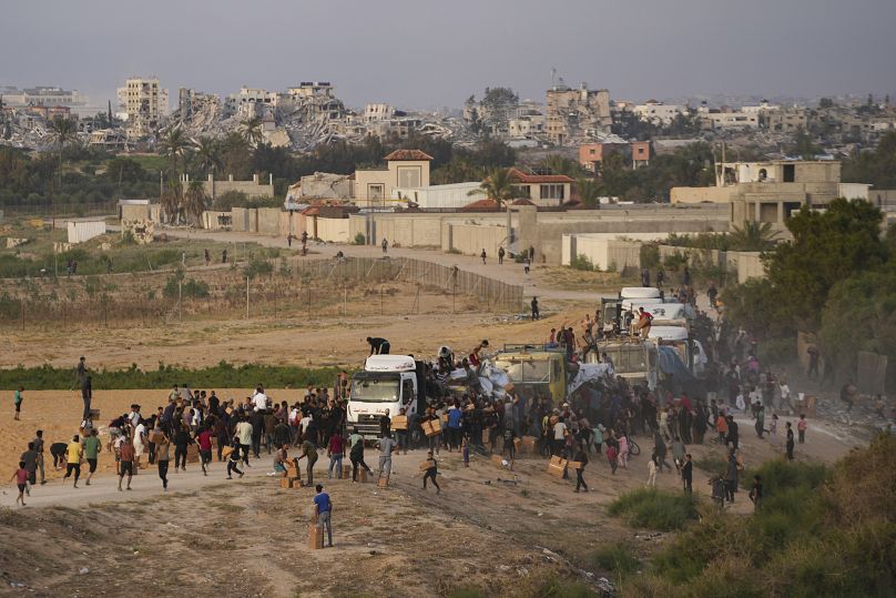 Des Palestiniens prennent d'assaut des camions chargés d'aide humanitaire amenés via un nouveau quai construit par les États-Unis dans le centre de Gaza, le 18 mai 2024.