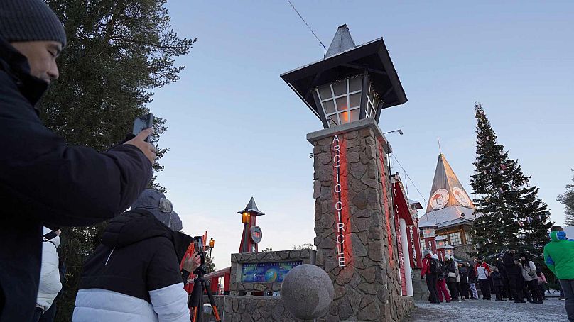 Des touristes prennent des photos au village du Père Noël, au bord du cercle polaire arctique, à Rovaniemi, en Finlande, le mercredi 4 décembre 2024. 