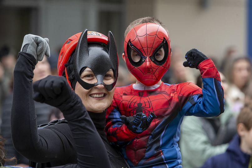 Un enfant habillé en Spiderman pose avec un alpiniste du Kosovo déguisé en super-héros livrant des cadeaux de Noël à Pristina, le 13 décembre 2024.