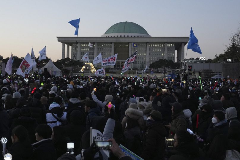 Les participants réagissent après avoir appris que le parlement sud-coréen a voté la destitution du président Yoon Suk-yeol devant l'Assemblée nationale à Séoul.