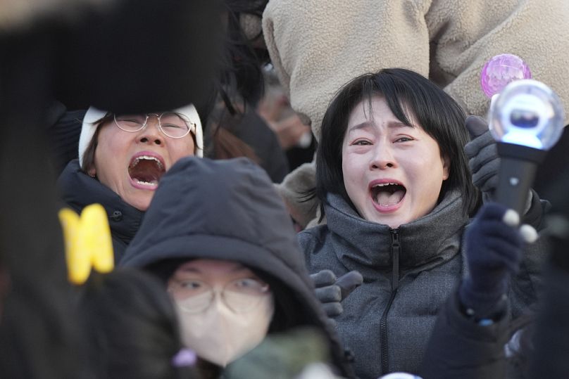 Les participants réagissent après avoir appris la nouvelle de la destitution du président sud-coréen Yoon Suk-yeol devant l'Assemblée nationale à Séoul