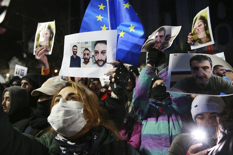 Des manifestants brandissent des portraits de militants blessés lors de manifestations alors qu'ils participent à un rassemblement antigouvernemental devant le Parlement à Tbilissi, le 14 décembre 2024.