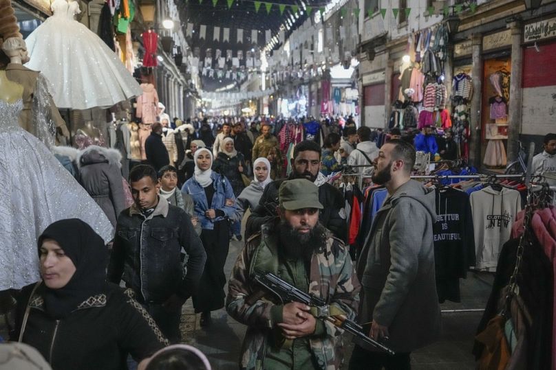 DOSSIER - Un combattant de l'opposition armée marche parmi les clients du marché d'Al-Hamidiyeh, à l'intérieur de la vieille ville fortifiée de Damas, en Syrie, le mardi 10 décembre 2024. 