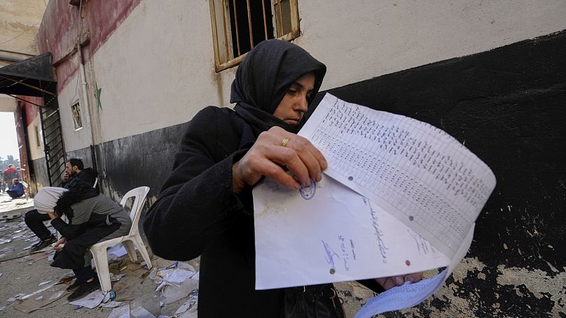 Une femme examine une liste de noms dans un document trouvé sur le sol de la tristement célèbre prison militaire de Saydnaya, juste au nord de Damas, en Syrie, le lundi 9 décembre 2024.