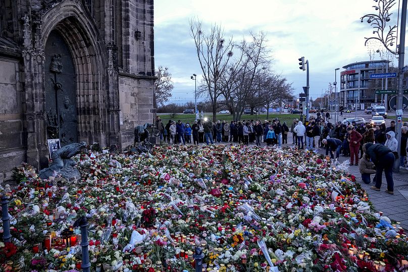 Des gens déposent des fleurs et allument des bougies devant l'église Johannis, près du marché de Noël de Magdebourg, le 22 décembre 2024.