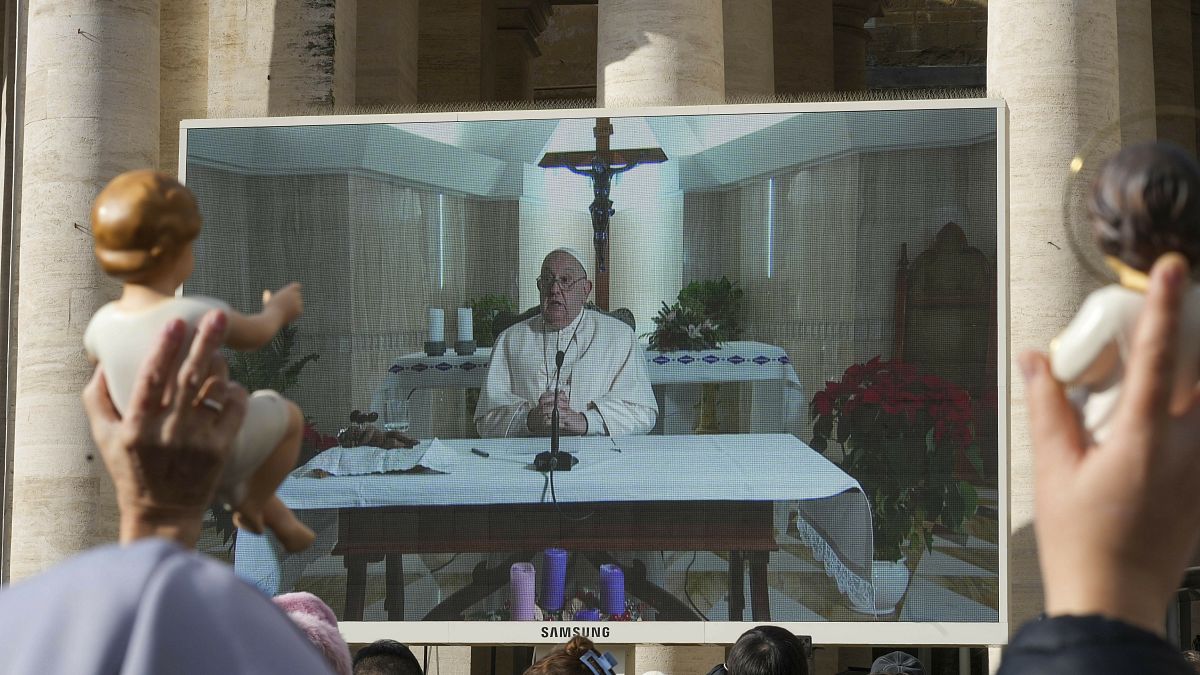 People watch the Pope’s Sunday blessing on a screen on St. Peter