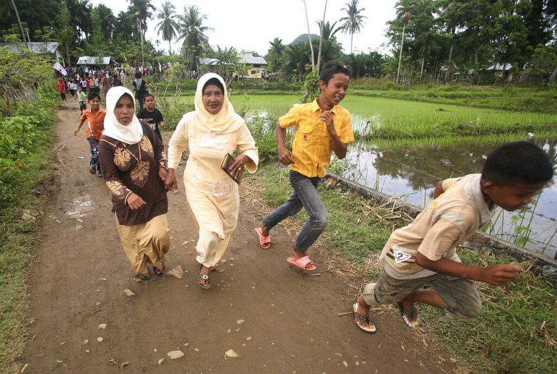 Des gens courent vers les hauteurs lors d'un exercice de tsunami organisé à l'occasion du cinquième anniversaire du tsunami de l'océan Indien à Lhoong, dans la province d'Aceh, en Indonésie, en 2009.