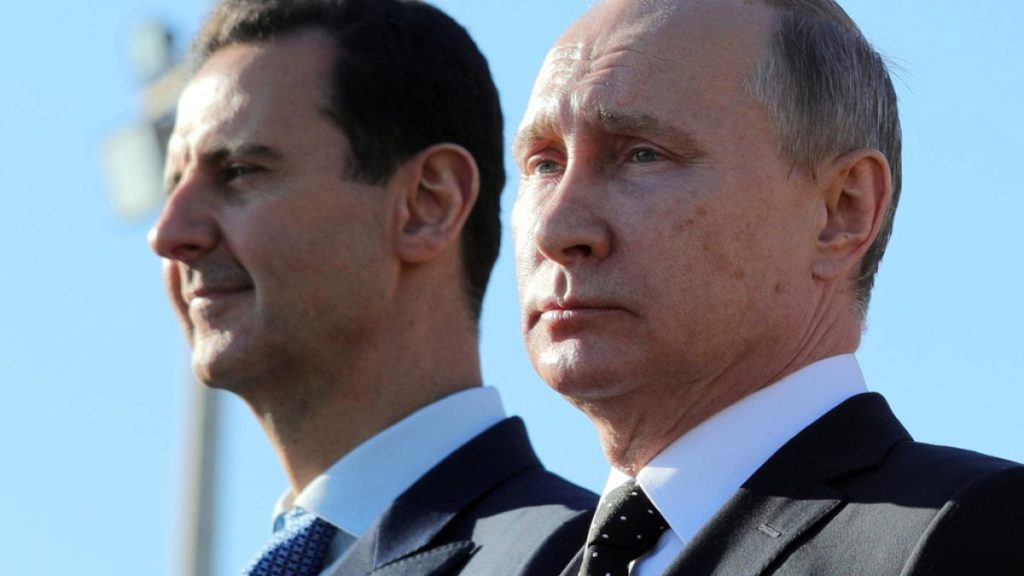 Russian President Vladimir Putin, right, and Syrian President Bashar Assad watch troops marching at the Hemeimeem air base in Syria, on Dec. 11, 2017.