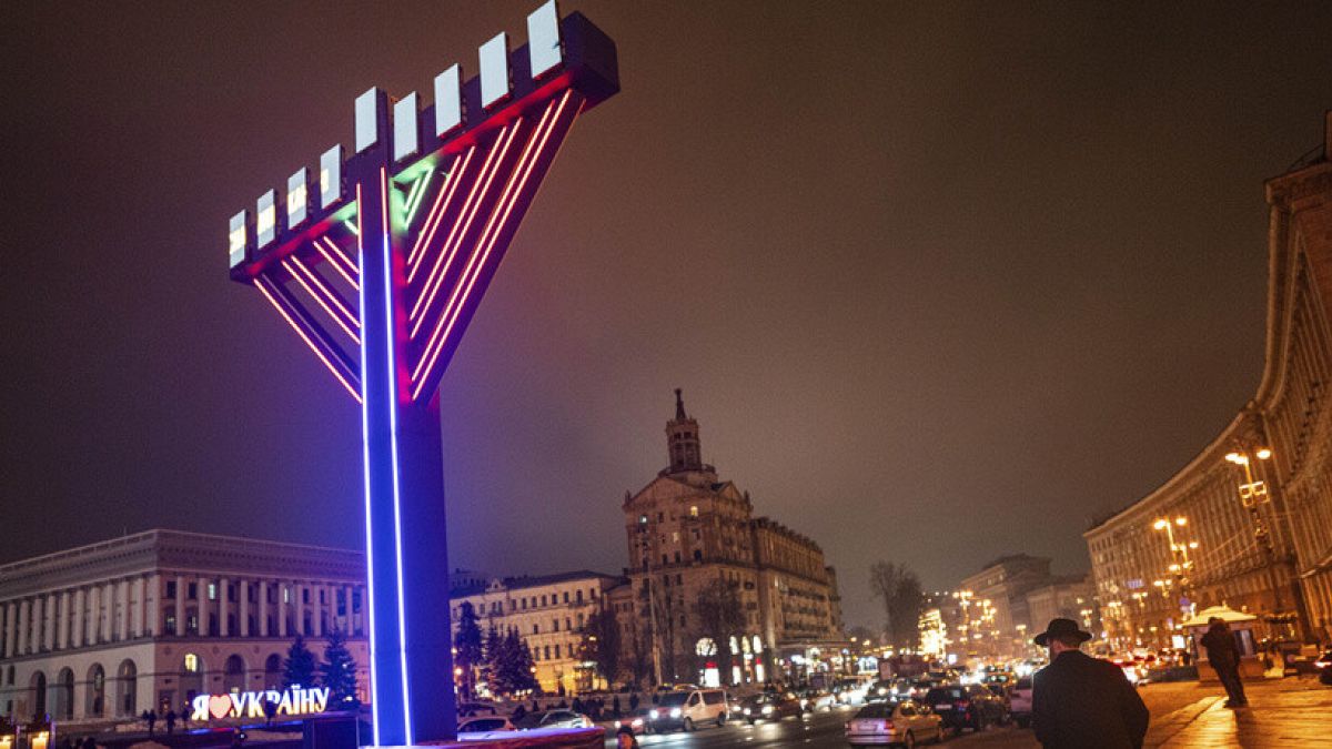 A man walks past menorah after lighting candles marking the fifth night of the Jewish holiday of Hanukkah on Independence square in Kyiv, Ukraine, Monday, Dec. 11, 2023