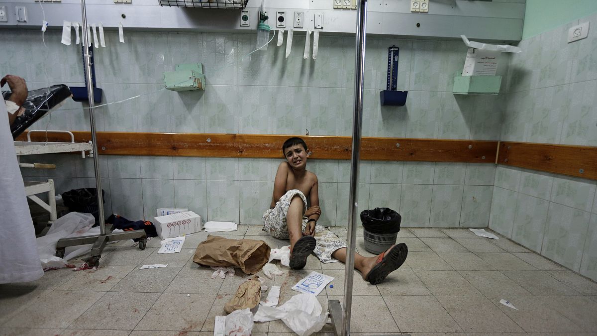 A Palestinian boy who was wounded in an Israeli strike sits on the floor at the emergency room of the Kamal Adwan hospital, 3 August, 2014