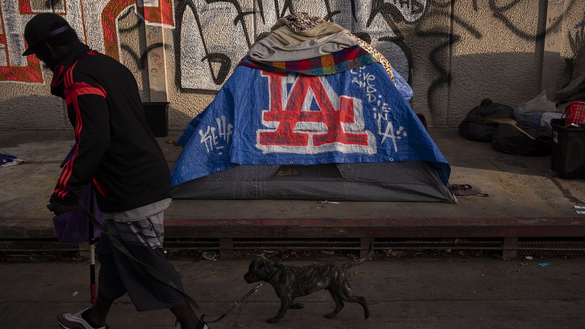 FILE - A man walks past a homeless encampment in downtown Los Angeles, Wednesday, Oct. 25, 2023. (AP Photo/Jae C. Hong, File)