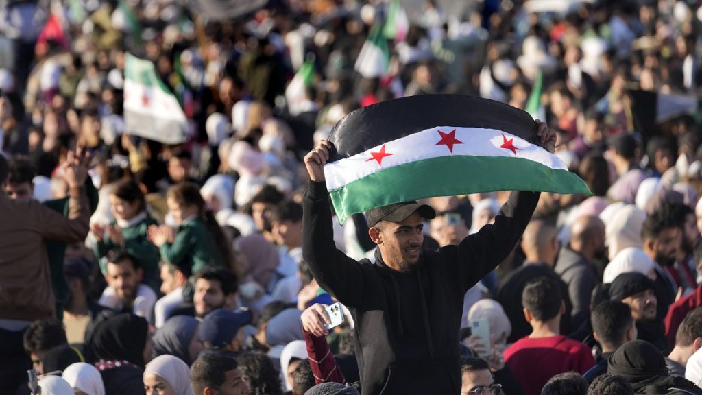 A Syrian man waves a revolutionary flag during a celebration in Damascus, 13 December, 2024