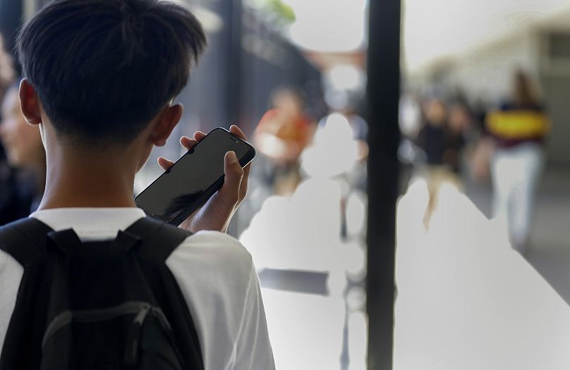 Aux États-Unis, un étudiant utilise son téléphone portable après avoir déverrouillé la pochette qui le protège de son utilisation pendant la journée scolaire.