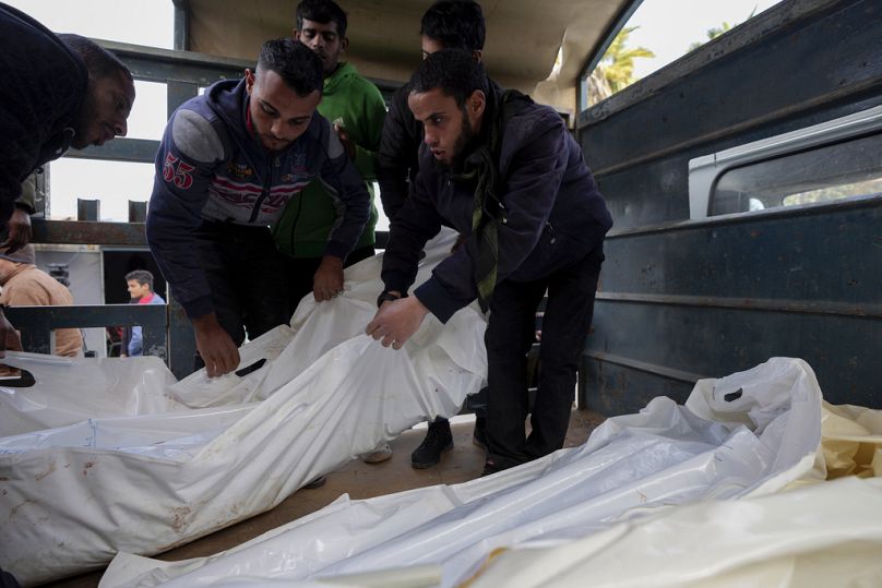 Les Palestiniens portent des sacs blancs contenant les corps des personnes tuées lors des frappes aériennes israéliennes nocturnes sur le camp de réfugiés de Maghazi, à l'hôpital Al-Aqsa