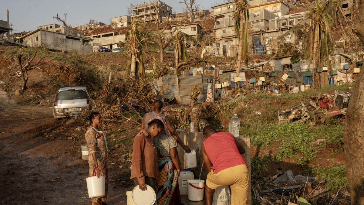 People line up to collect water in Barakani, Mayotte, home Saturday, Dec. 21, 2024.