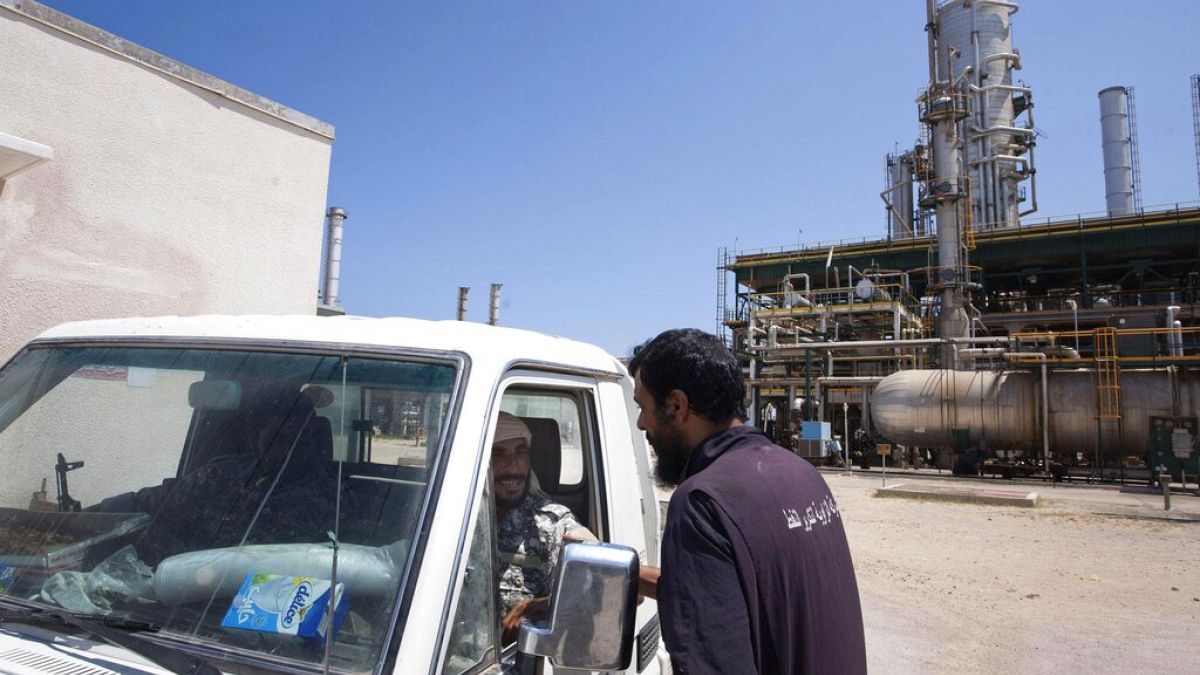 FILE - Libyan worker chats with two rebels who patrol an oil refinery controlled by anti-Gadhafi forces on the western outskirtS of Zawiya, Aug. 19, 2011