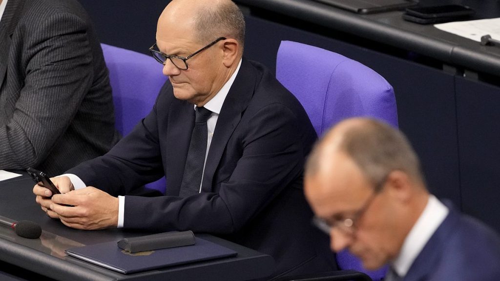 Outgoing Chancellor Olaf Scholz checks his phone in the German parliament.