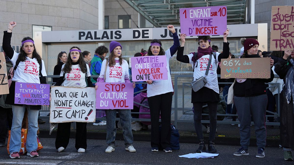 Activists hold posters in front of the Palace of Justice during a women