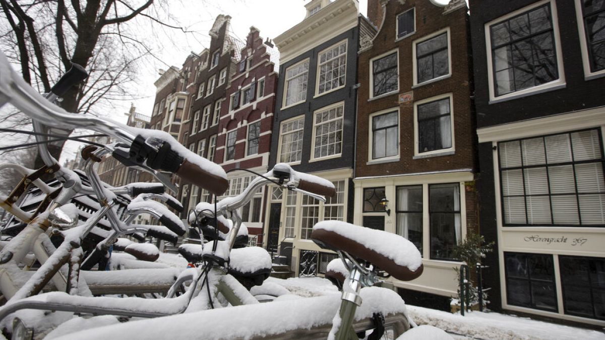 Snow-covered bicycles are parked outside canal houses in the centre of Amsterdam. 7 February 2021.