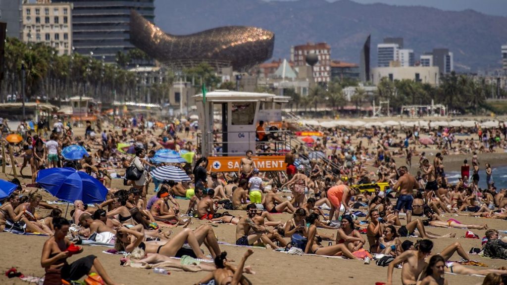 People sunbathe on the beach in Barcelona, Spain