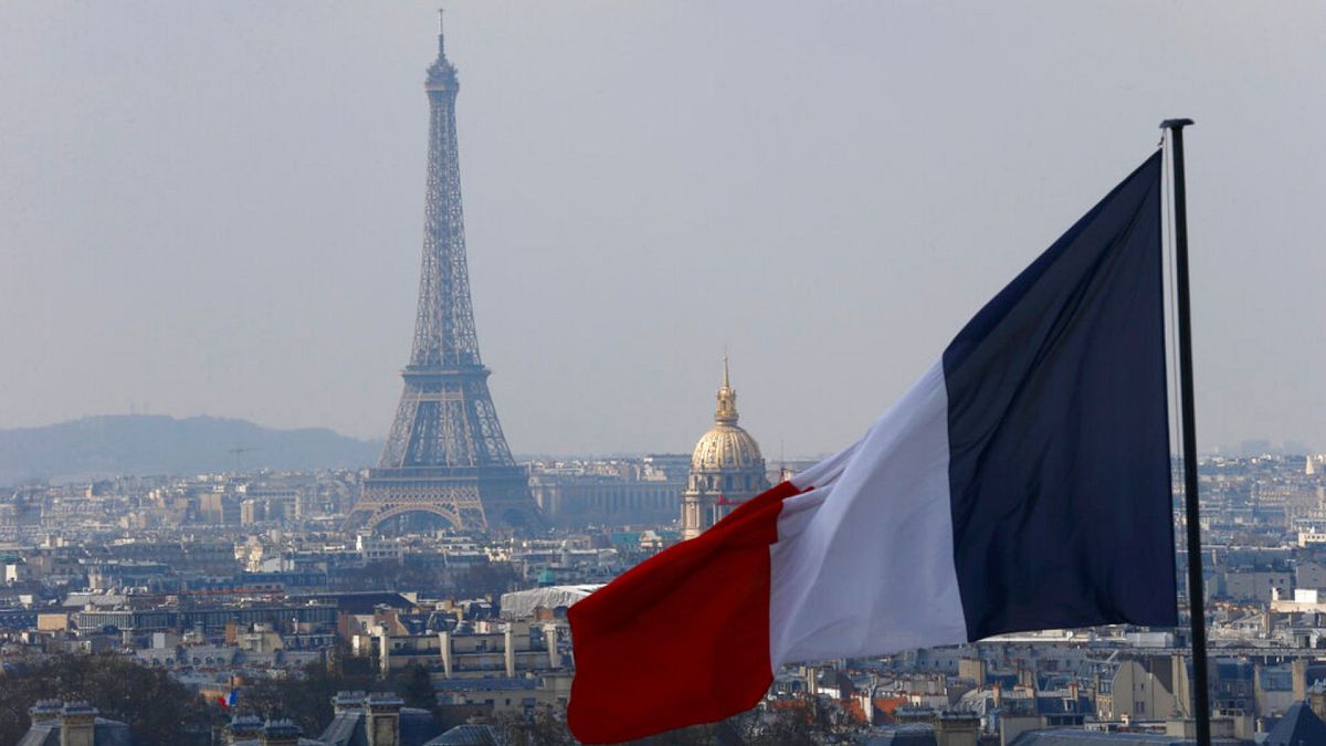 The French flag above the skyline of the French capital with the Eiffel Tower, The Invalides Dome and roof tops are seen from the colonnade of the Pantheon Dome in Paris.