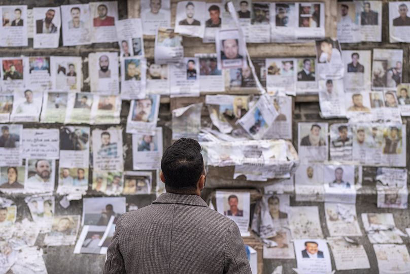 Un homme inspecte les portraits de personnes disparues dont les familles affirment qu'ils ont été capturés par le régime d'al-Assad, placardés sur un monument à Damas, le 28 décembre 2024.