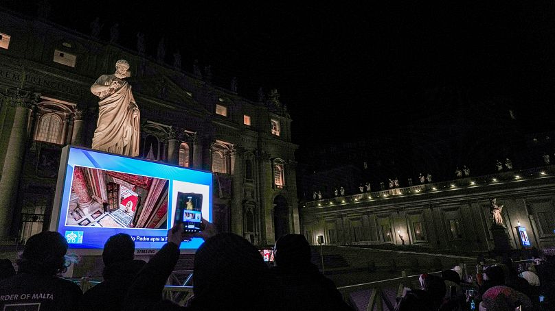 Un moniteur géant sur la place Saint-Pierre montre le pape François franchissant la porte sainte de la basilique Saint-Pierre au Vatican, le mardi 24 décembre 2024.