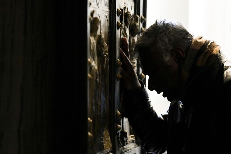 Un homme baisse la tête en prière à la Porte Sainte de la Basilique Saint-Pierre au Vatican, le 25 décembre 2024.