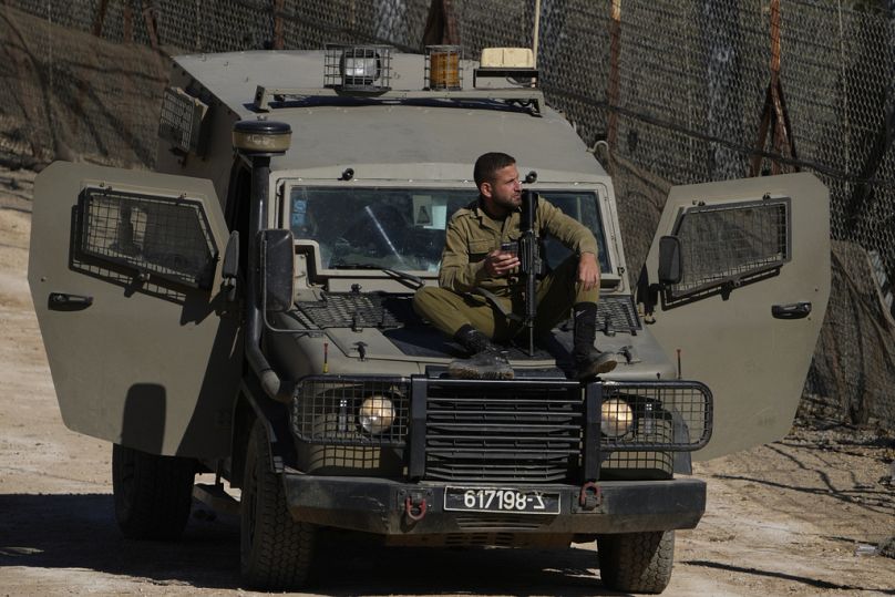 Un soldat israélien est assis sur un véhicule blindé à côté de la barrière de sécurité près de la ligne Alpha qui sépare le plateau du Golan sous contrôle israélien de la Syrie.