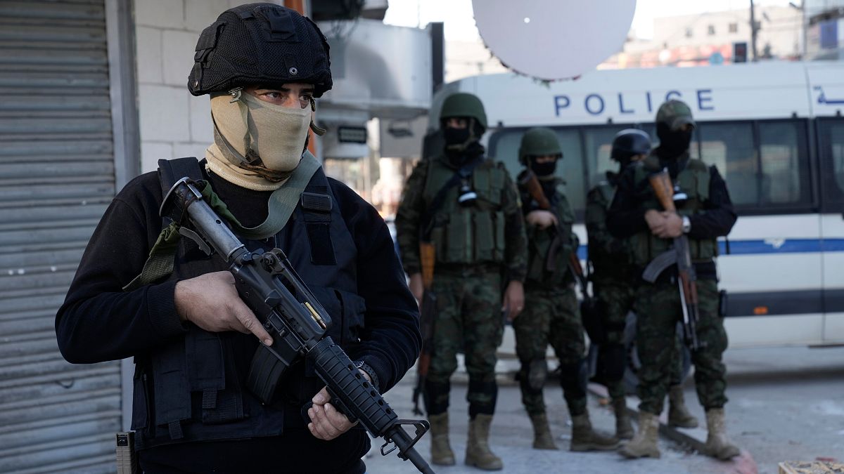 An officer from the Palestinian Authority clutches his gun as Palestinian security forces mount a major raid against militants in the Jenin refugee camp, Dec. 16, 2024.