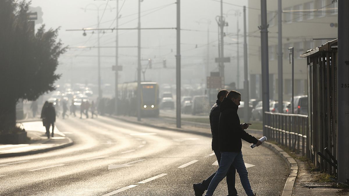 People cross the street shrouded by pollution haze as smog covers Sarajevo, Bosnia, in December 2024.