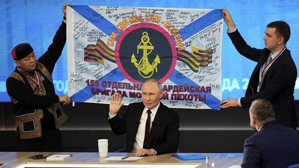 Men hold a replica of the banner of the 155th Marine Brigade of the Pacific Fleet, during Russian President Vladimir Putin