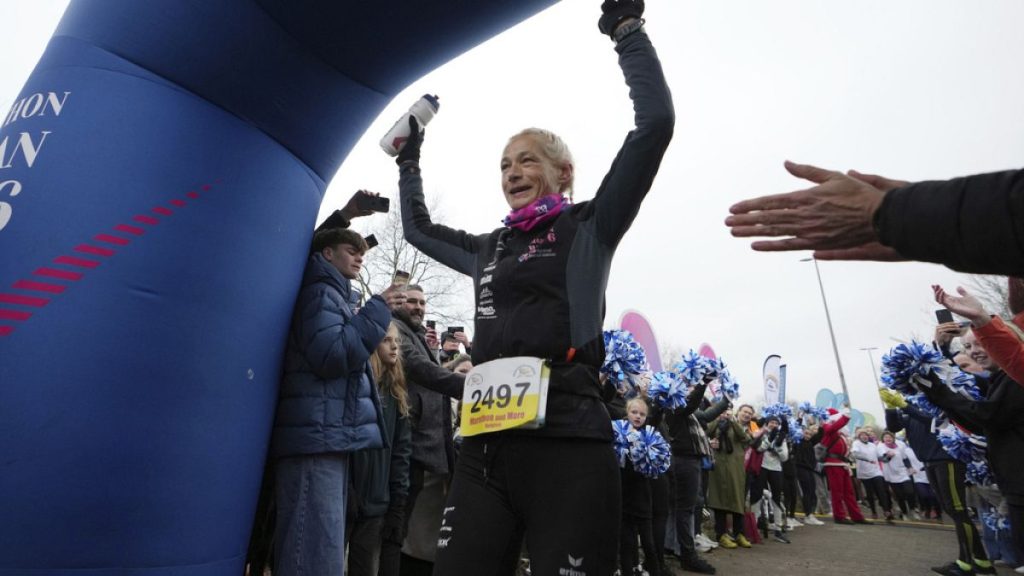 Belgian ultra runner Hilde Dosogne, center, is cheered on as she crosses the finish line during her 366th consecutive marathon in Ghent, Belgium, Tuesday, Dec. 31, 2024