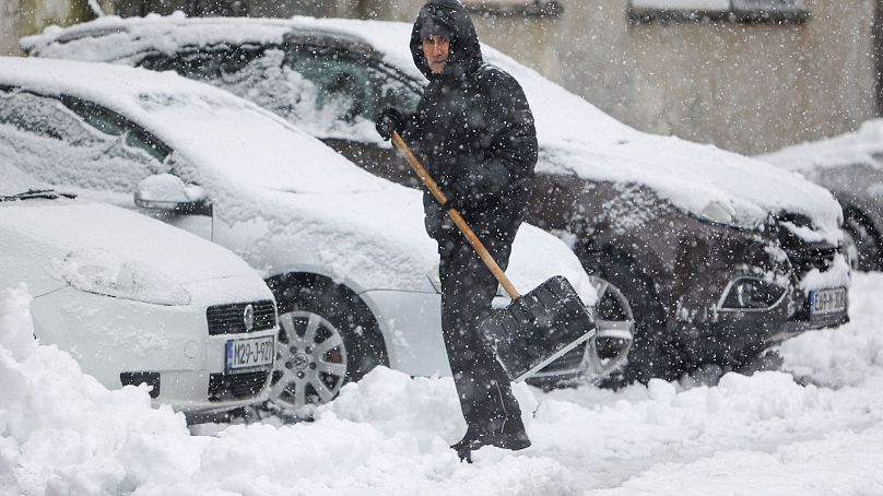 Un homme pellete la neige de la rue lors de fortes chutes de neige à Bihac, en Bosnie.