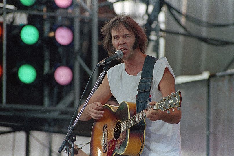 Neil Young, jouant d'une guitare acoustique Gibson J-200, se produit lors du concert Live Aid pour lutter contre la famine au stade JFK de Philadelphie, en Pennsylvanie, le 13 juillet 1985.